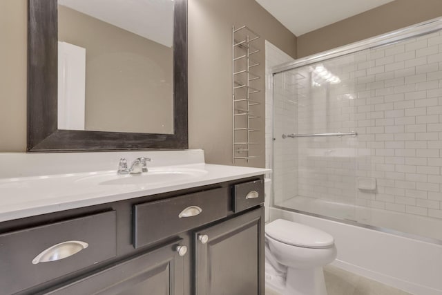 bathroom featuring toilet, combined bath / shower with glass door, and vanity