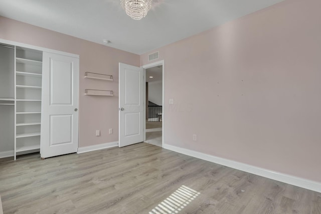 unfurnished bedroom featuring a closet, visible vents, baseboards, and wood finished floors