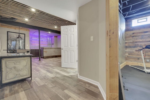 corridor with wood walls, wood finished floors, and baseboards