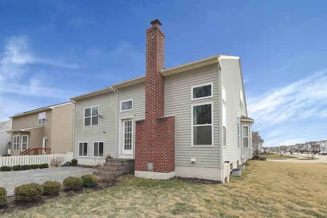 rear view of property with a yard, a chimney, a patio, entry steps, and fence