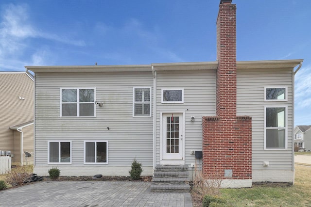 back of property featuring entry steps and a chimney