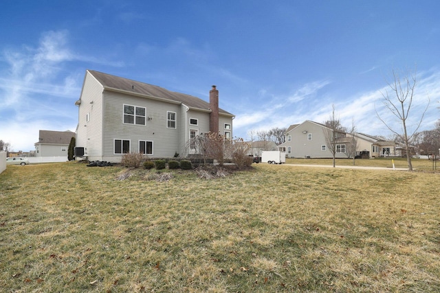 back of house featuring a lawn and a chimney