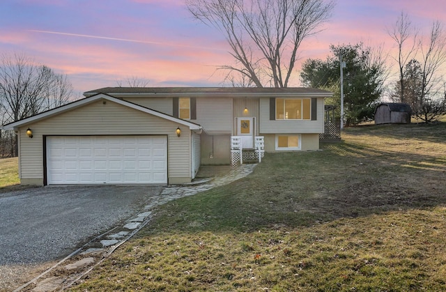 bi-level home with aphalt driveway, an attached garage, a storage unit, and a front yard