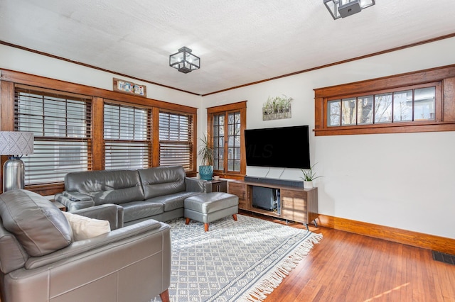 living room with visible vents, ornamental molding, a textured ceiling, wood finished floors, and baseboards