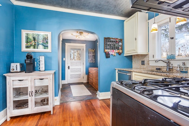 kitchen with arched walkways, dishwasher, gas range, wood finished floors, and light countertops