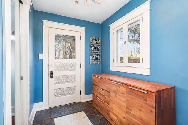 doorway featuring baseboards and stone tile floors