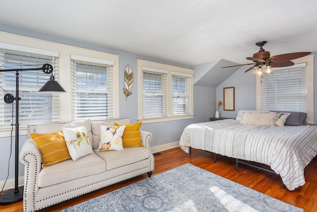 bedroom with multiple windows, wood finished floors, a ceiling fan, and baseboards