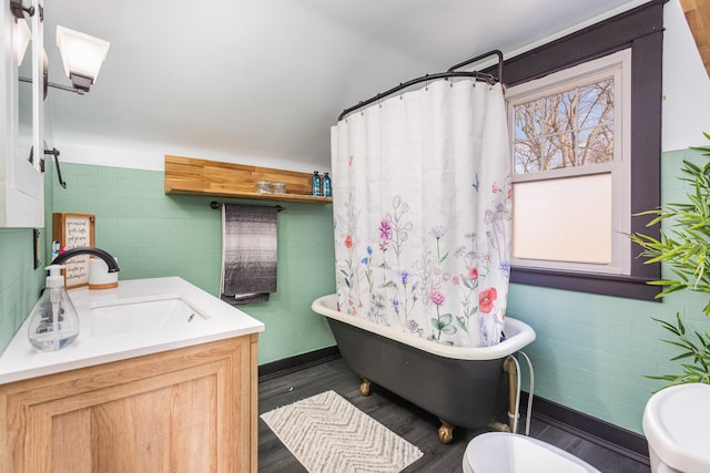 bathroom with a freestanding tub, toilet, wood finished floors, vanity, and a shower with curtain