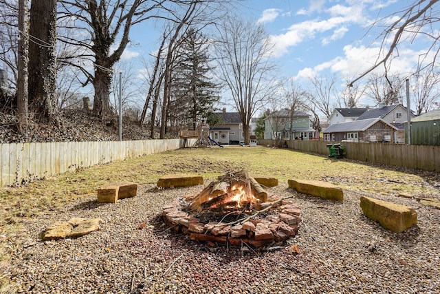 view of yard with an outdoor fire pit, a playground, and a fenced backyard