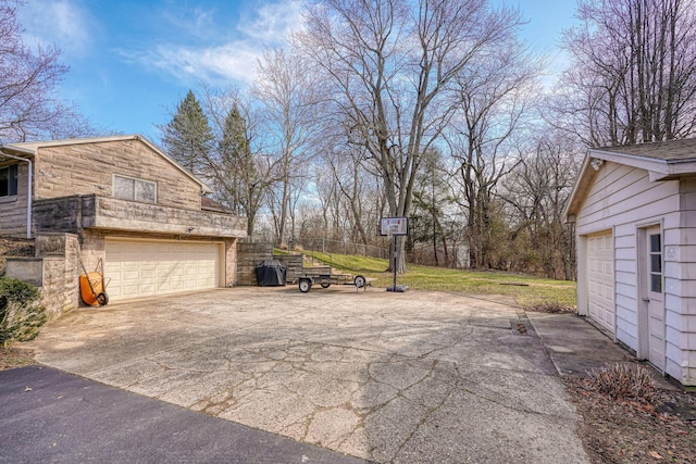 view of side of property featuring a garage, stone siding, driveway, and a yard