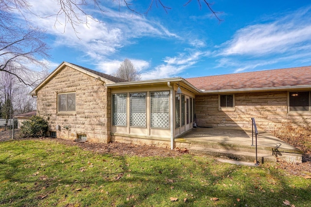 back of property with a lawn, stone siding, a patio, and a sunroom