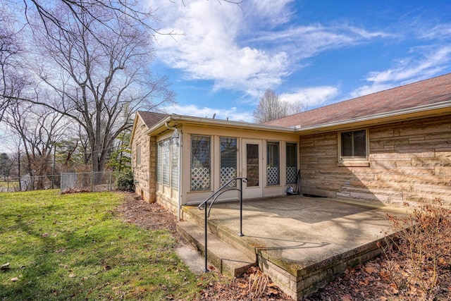 rear view of property with roof with shingles, a yard, a patio area, fence, and stone siding