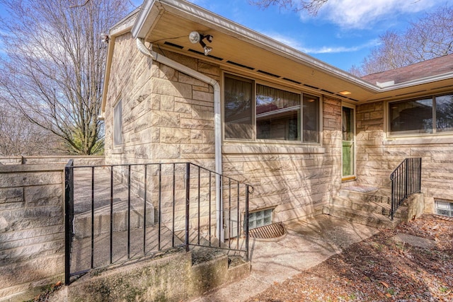 property entrance with stone siding and fence