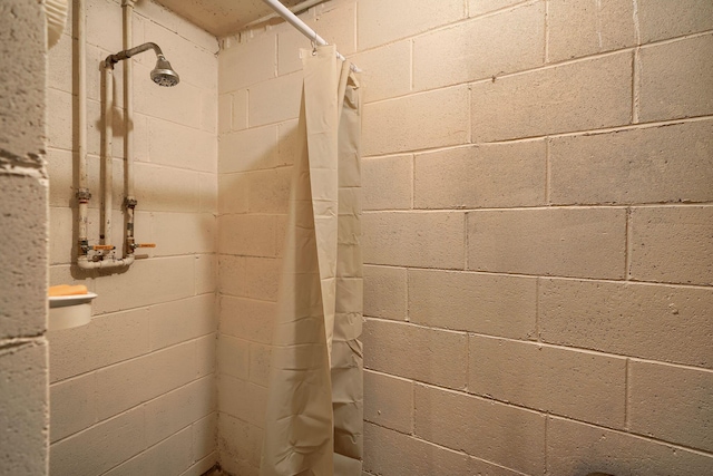 bathroom with a tile shower and concrete block wall