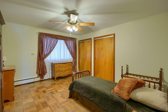 bedroom with a baseboard heating unit, a ceiling fan, and two closets