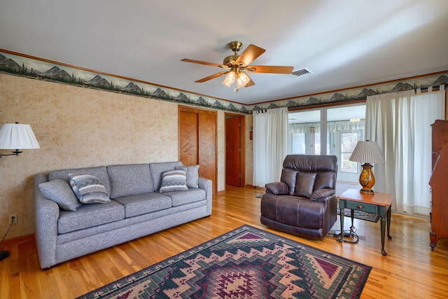 living area featuring crown molding, visible vents, a ceiling fan, wood finished floors, and baseboards