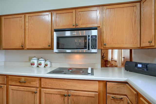 kitchen with tasteful backsplash, light countertops, stainless steel microwave, and electric stovetop