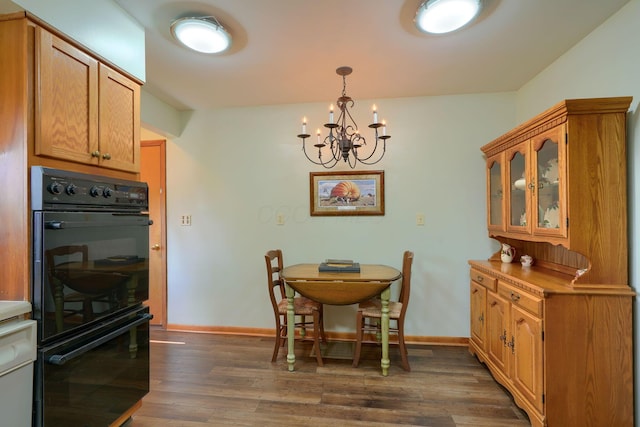 dining room with dark wood-style floors, a chandelier, and baseboards