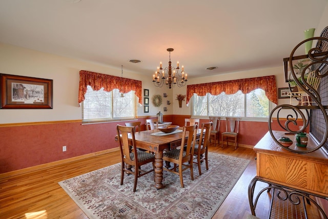 dining room with wainscoting, visible vents, plenty of natural light, and wood finished floors