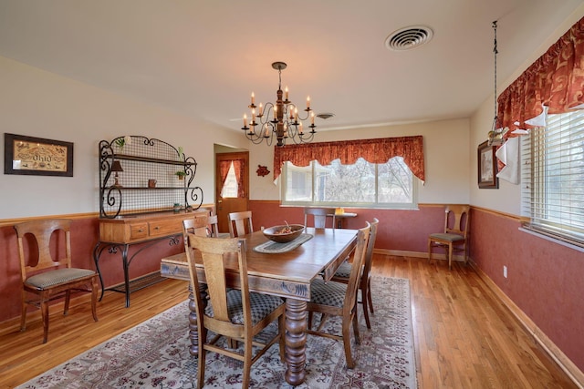 dining area featuring a chandelier, a wainscoted wall, visible vents, and wood finished floors