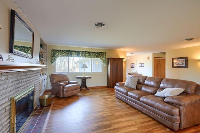 living room with light wood-type flooring, a fireplace, and visible vents