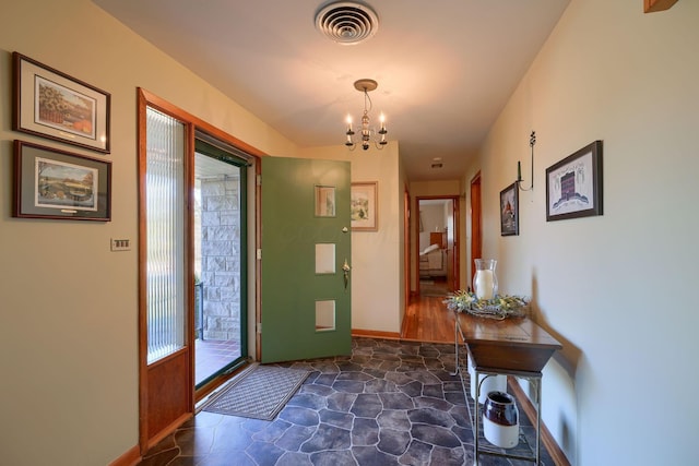 interior space with stone finish flooring, visible vents, a chandelier, and baseboards