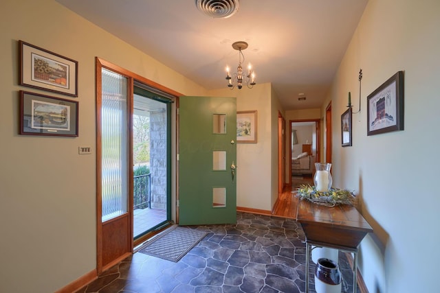 doorway to outside featuring stone finish flooring, visible vents, a notable chandelier, and baseboards