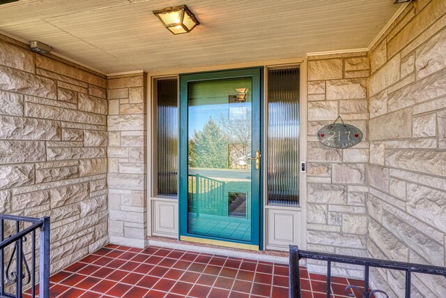 view of exterior entry with stone siding and covered porch