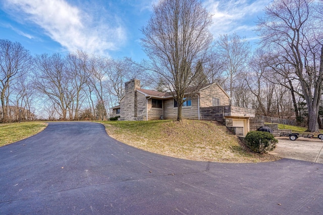 view of front of home featuring stone siding, driveway, and a chimney