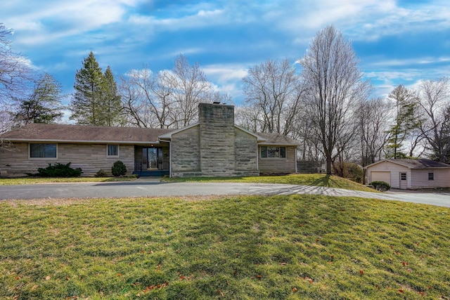 view of front of house featuring aphalt driveway, a garage, stone siding, a chimney, and a front yard