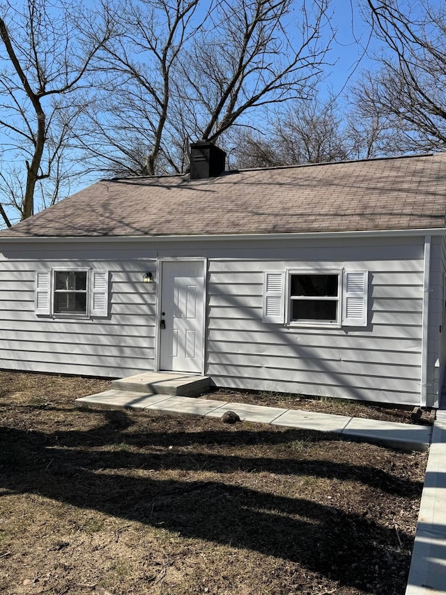 view of front of house with a chimney and roof with shingles