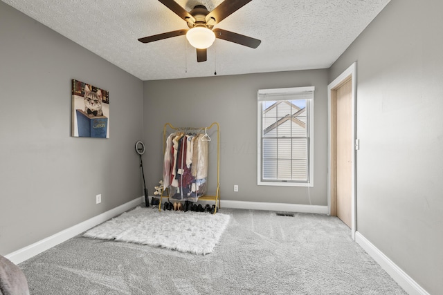 workout area featuring visible vents, baseboards, a ceiling fan, a textured ceiling, and carpet flooring