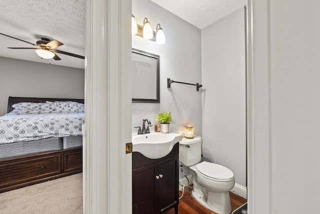 ensuite bathroom with toilet, ensuite bathroom, a ceiling fan, a textured ceiling, and vanity