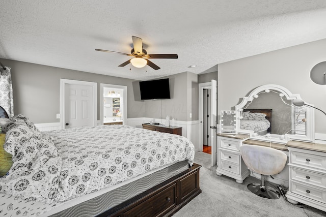 bedroom featuring light carpet, a textured ceiling, and a ceiling fan