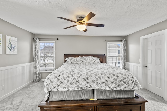 bedroom with light carpet, multiple windows, and wainscoting