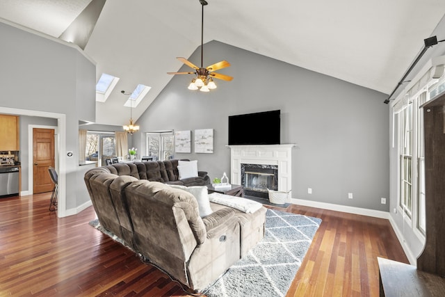 living room with baseboards, ceiling fan with notable chandelier, dark wood-style flooring, and a high end fireplace