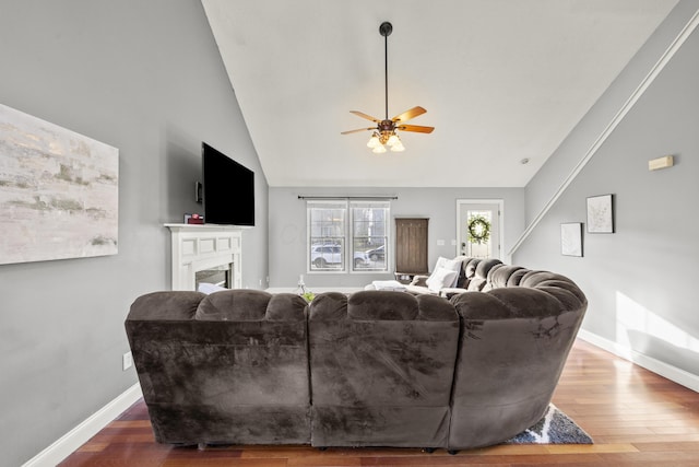 living room featuring vaulted ceiling, a fireplace, wood finished floors, and baseboards