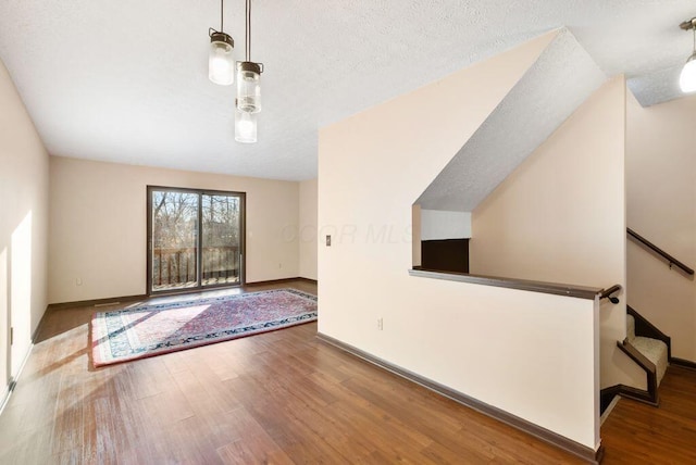 interior space with a textured ceiling, baseboards, and wood finished floors