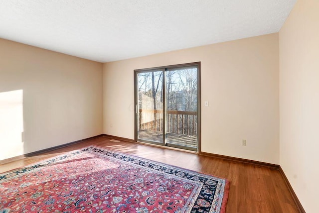 spare room with baseboards and wood finished floors