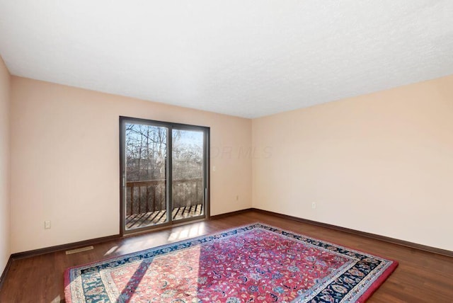 unfurnished room featuring wood finished floors, visible vents, and baseboards