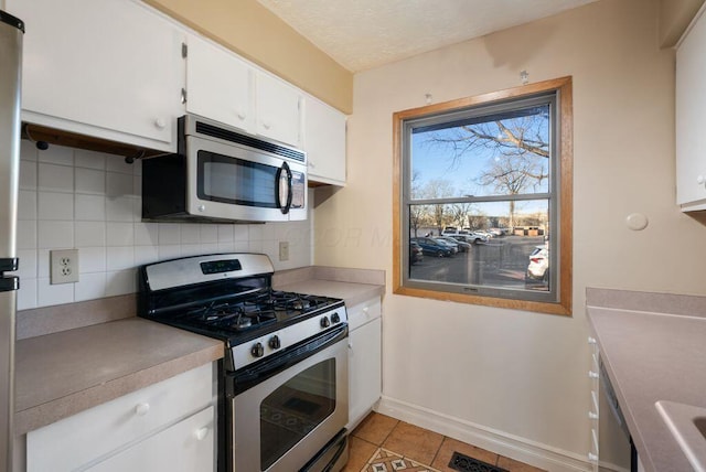 kitchen featuring stainless steel appliances, light countertops, backsplash, and light tile patterned floors