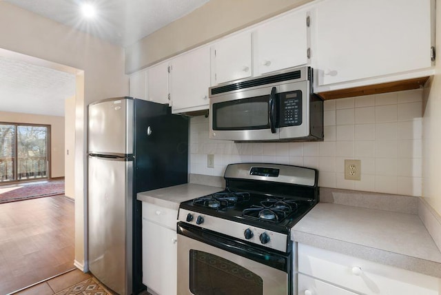 kitchen featuring appliances with stainless steel finishes, light countertops, backsplash, and white cabinetry