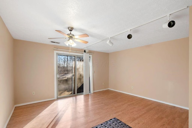 unfurnished room featuring light wood finished floors, visible vents, baseboards, ceiling fan, and a textured ceiling