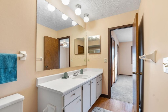 bathroom featuring a textured ceiling, toilet, wood finished floors, vanity, and baseboards