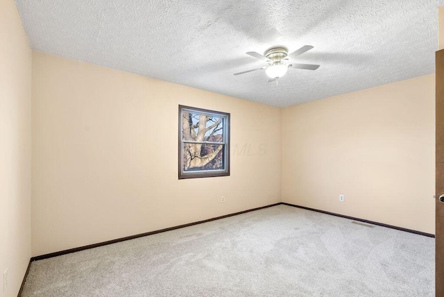 carpeted empty room featuring ceiling fan, a textured ceiling, and baseboards