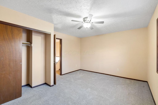 unfurnished bedroom featuring a closet, light colored carpet, ceiling fan, a textured ceiling, and baseboards