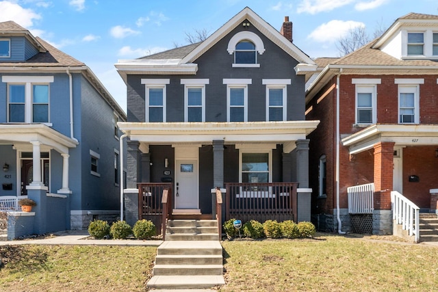 view of front of home with covered porch, a chimney, and a front lawn