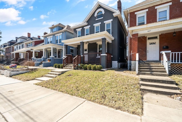 townhome / multi-family property featuring brick siding, a residential view, a porch, and a front yard