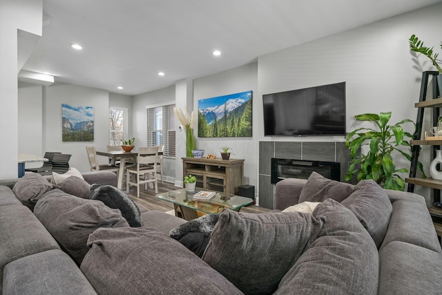 living room with a tiled fireplace, recessed lighting, and wood finished floors