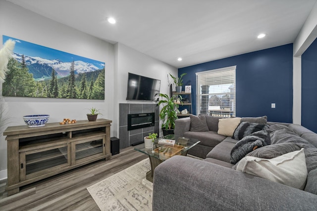 living room with recessed lighting, wood finished floors, and a tiled fireplace